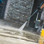 Men Washing Driveway Using Pressure Washer. Spring Time Cleaning.